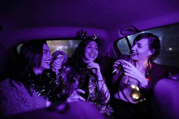 Three modern young women celebrating New Year's Eve at the back-seat of a car